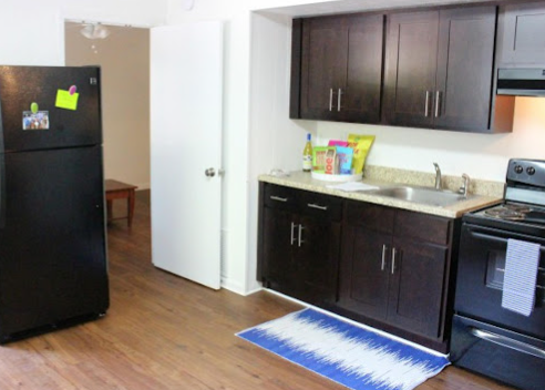 a kitchen with dark cabinets and a blue rug
