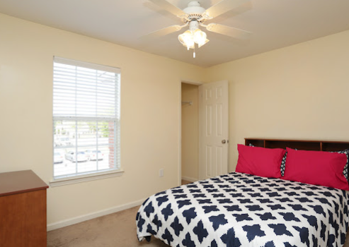 a bed with a pink pillow and a white ceiling fan
