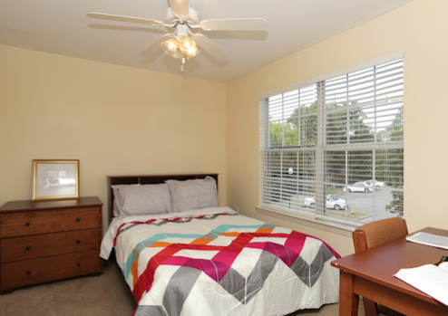 a bed with a colorful blanket and a ceiling fan